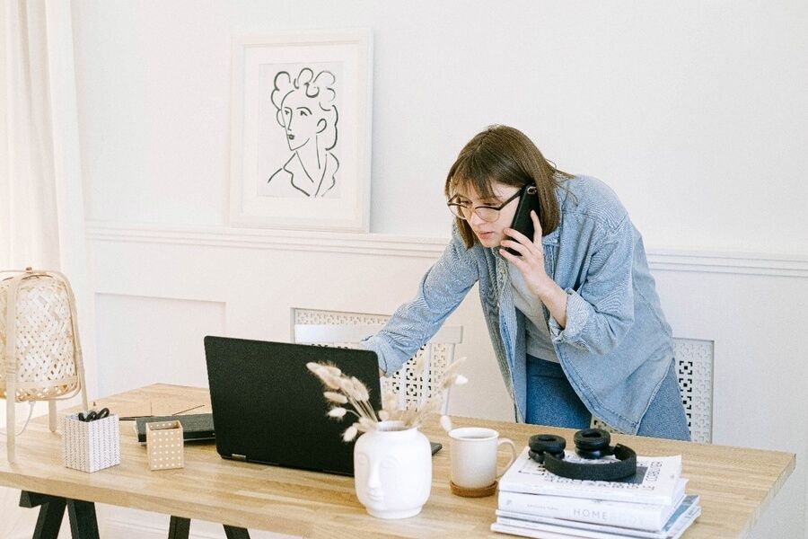 kobieta rozmawiająca przez telefon przy laptopie