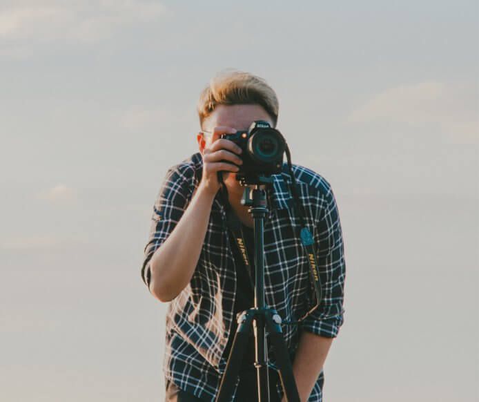 Fotograf podczas pracy z aparatem na statywie