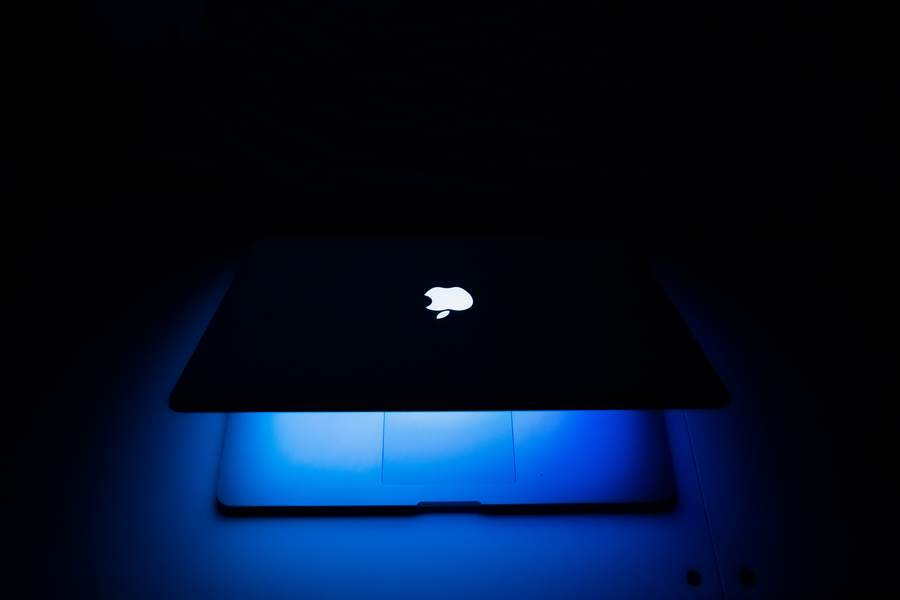 W połowie zamknięty laptop, z ekranem święcącym na niebiesko w ciemnym miejscu