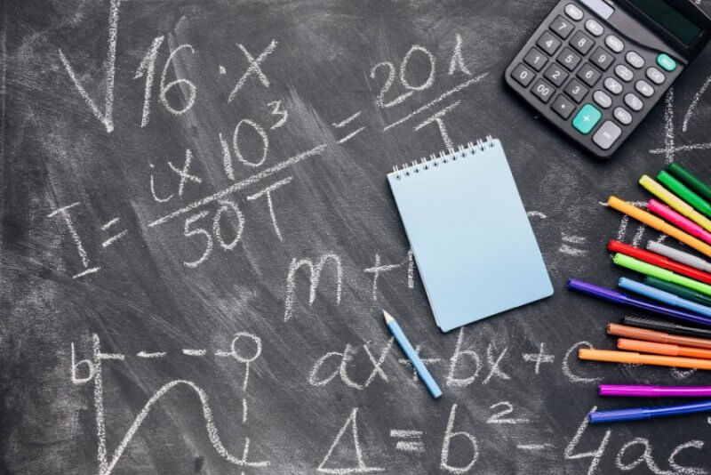 Kalkulator, notatnik i działania matematyczne na tablicy
