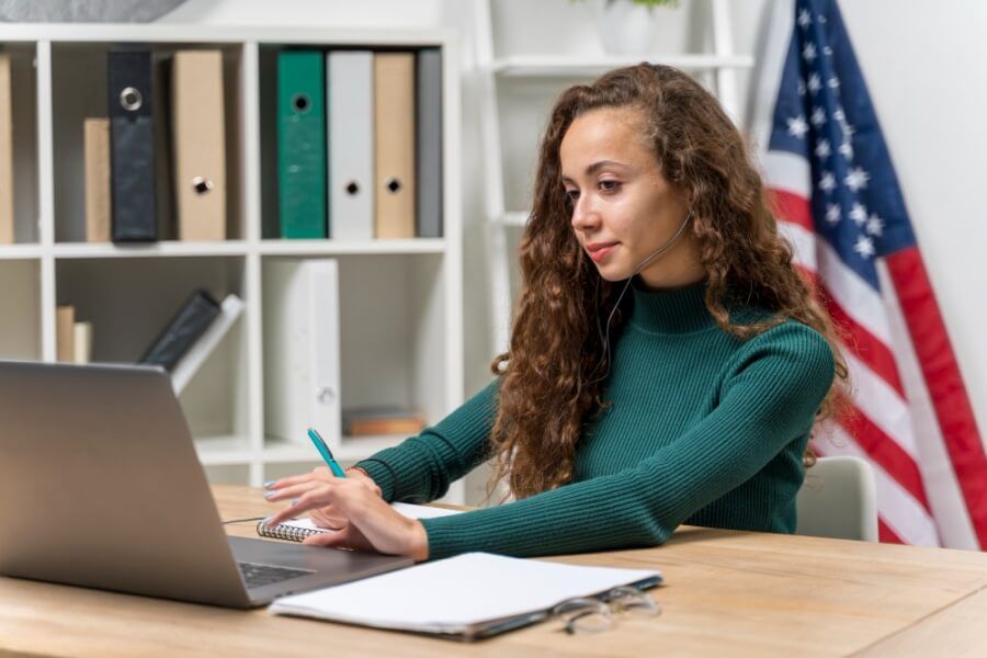 Kobieta w trakcie nauki języka angielskiego online i flaga USA